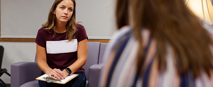 Person with a clipboard listening to another person talk.