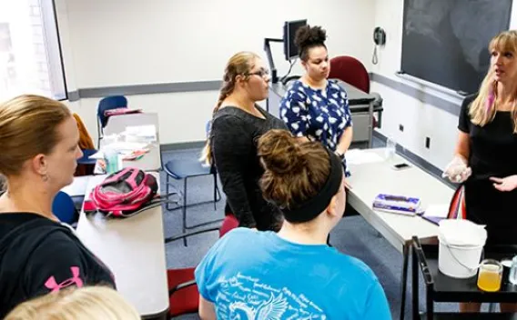 Professor talking with a group of students in a classroom