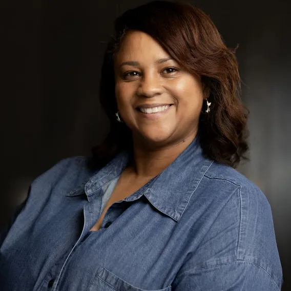 Professional headshot woman with medium-long brown hair, wearing denim shirt